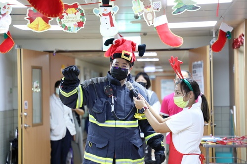 十大傑出青年獲獎者宋明哲身穿消防員服裝，向孩子們介紹自己的職業