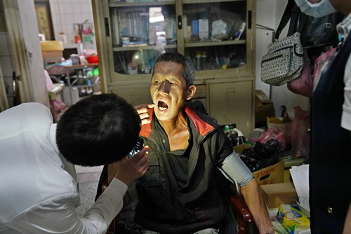 放射腫瘤科主治醫師廖彥翔透過手機手電筒燈光為許先生檢查口腔。