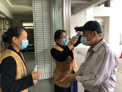醫療志工在門診大廳協助民眾測量體溫與手部消毒