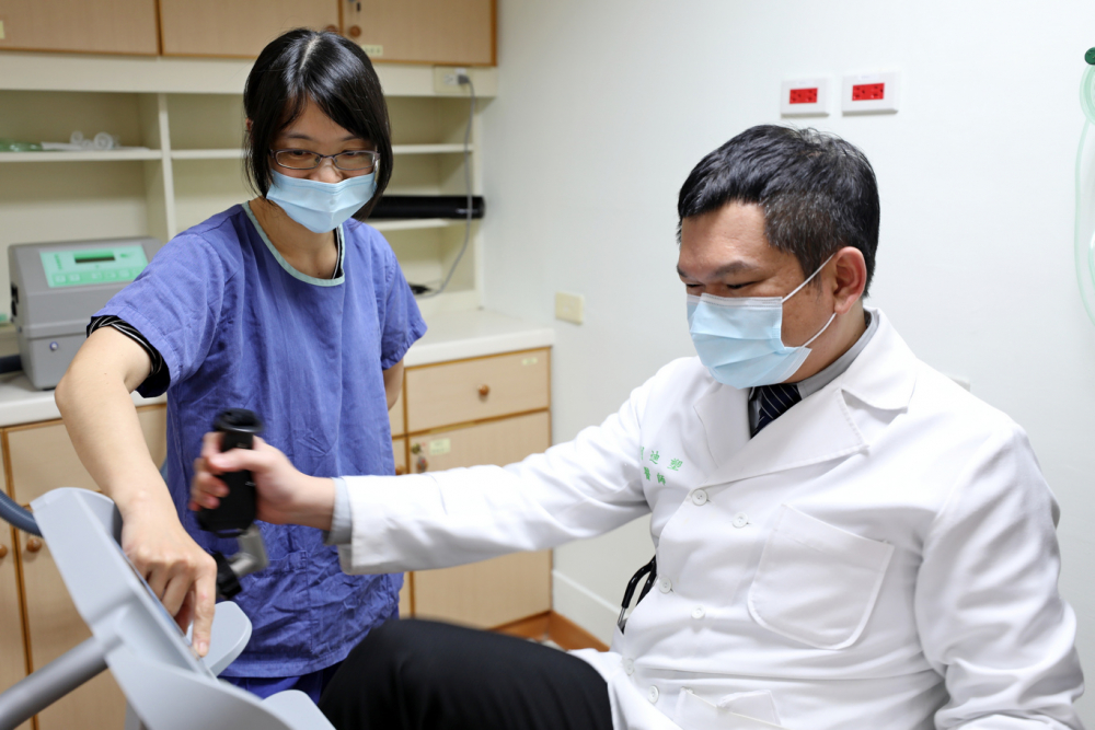 呼吸治療師陳宜榛和劉迪塑醫師示範如何使用肺復健器具「靠背式橢圓機」，達到訓練心肺及股四頭肌的效果。