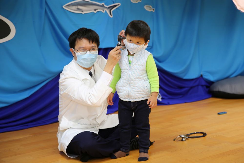 花蓮慈院小兒部兒童社區醫療科陳明群主任(左)，讓小朋友體驗照耳鏡不可怕。