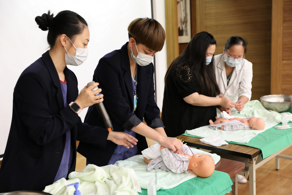花蓮慈院護兒中心護理師曹雅晴(左)與團隊，帶著爸爸、媽媽一起練習幫寶寶沐浴